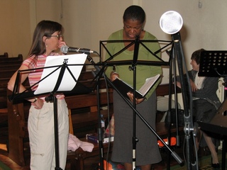 Image of a couple of group members sorting out the song sheets.